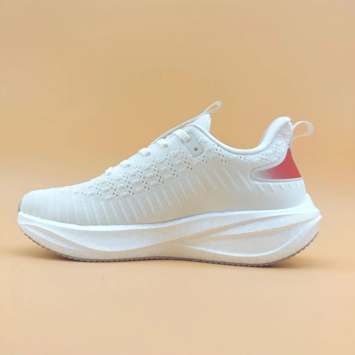 White sneaker with pink heel detail.