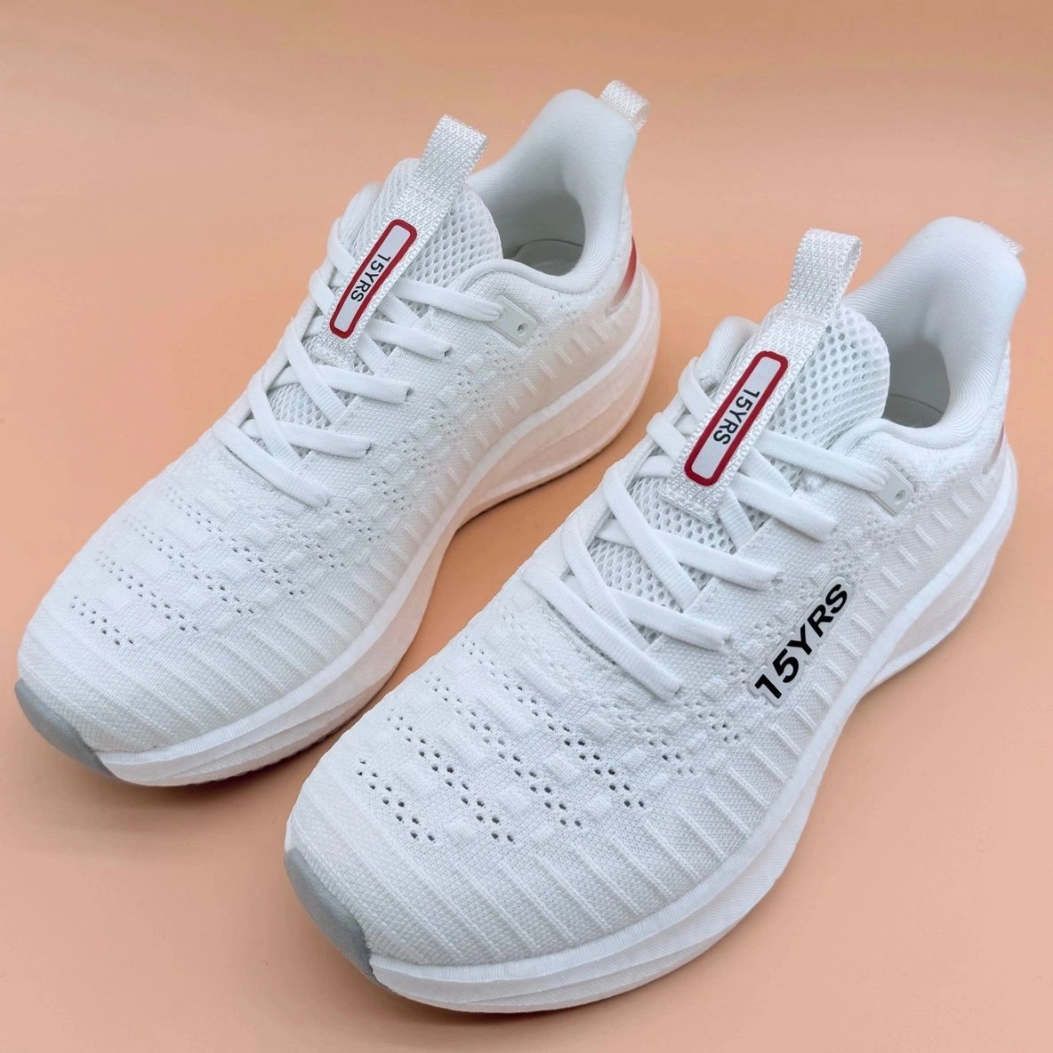White athletic shoes on peach background.